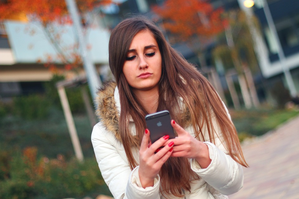 Young Woman Using iPhone Outdoors