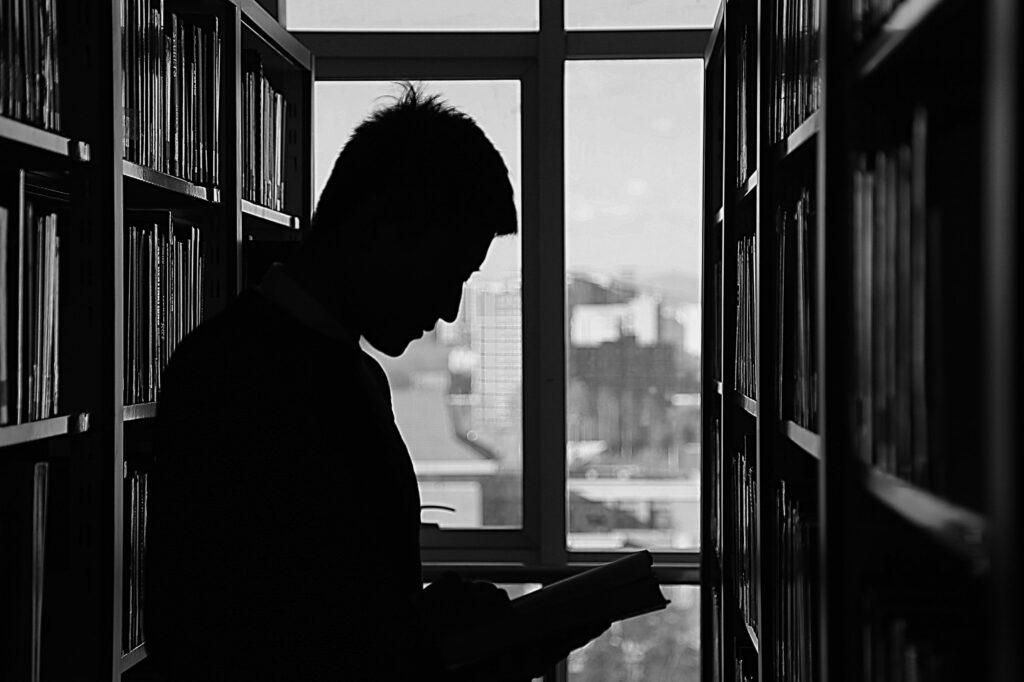 Silhouette of a man reading books in a library