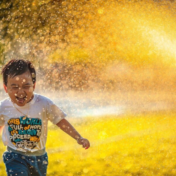 Laughing child running through sprinklers