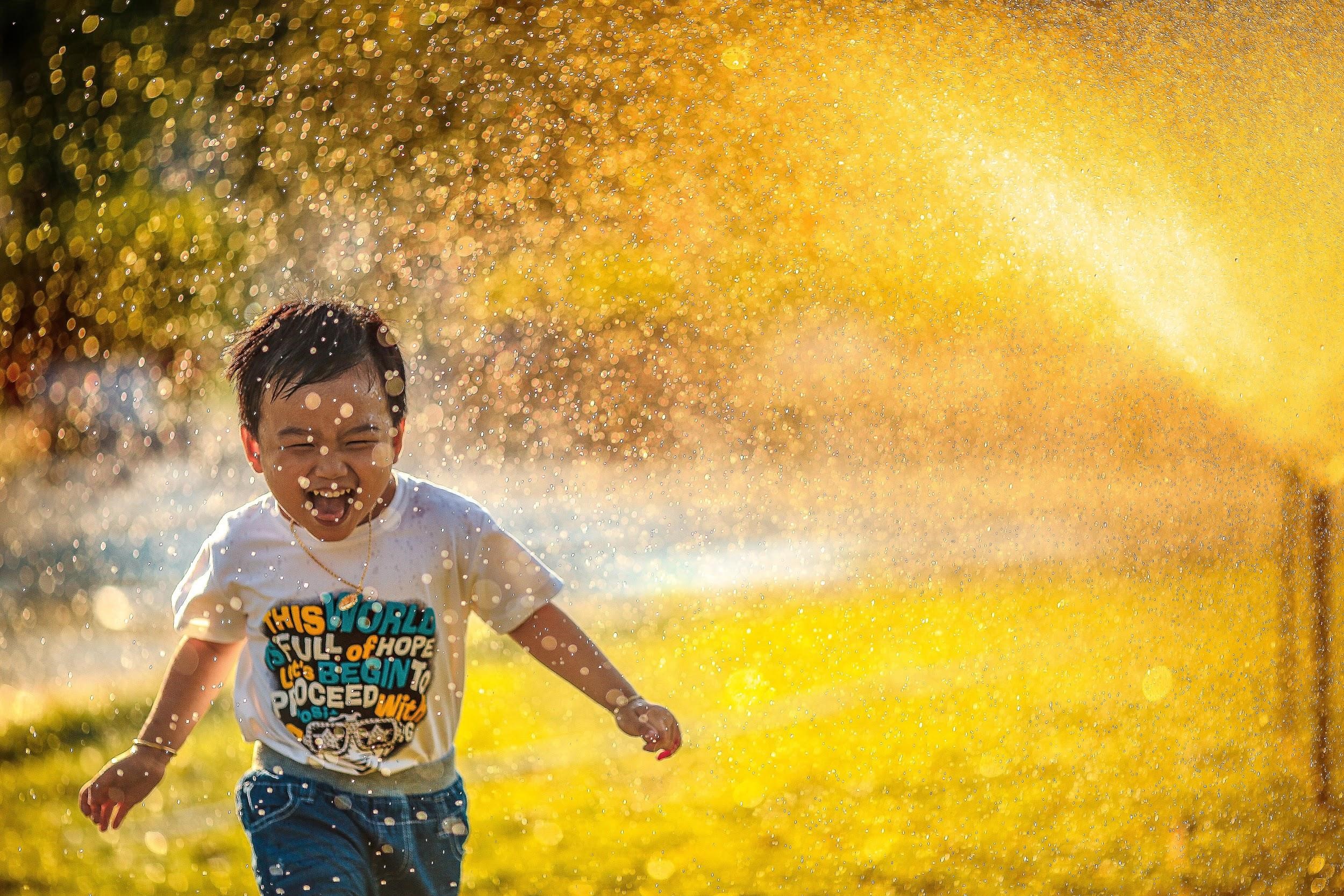 Laughing child running through sprinklers