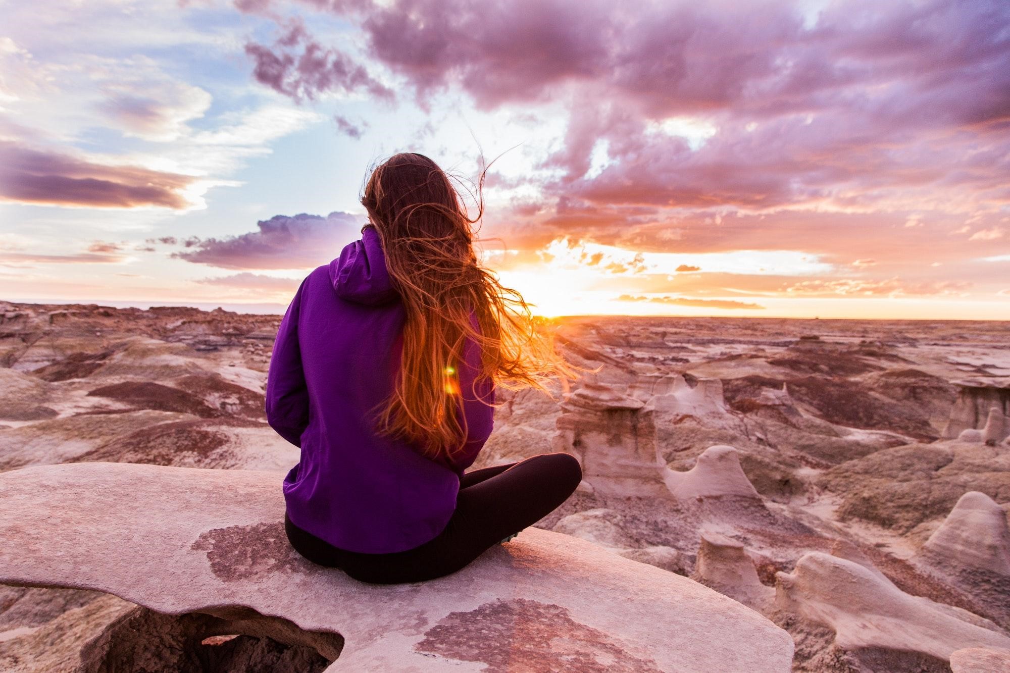 Woman sat on a rock watching the sunset