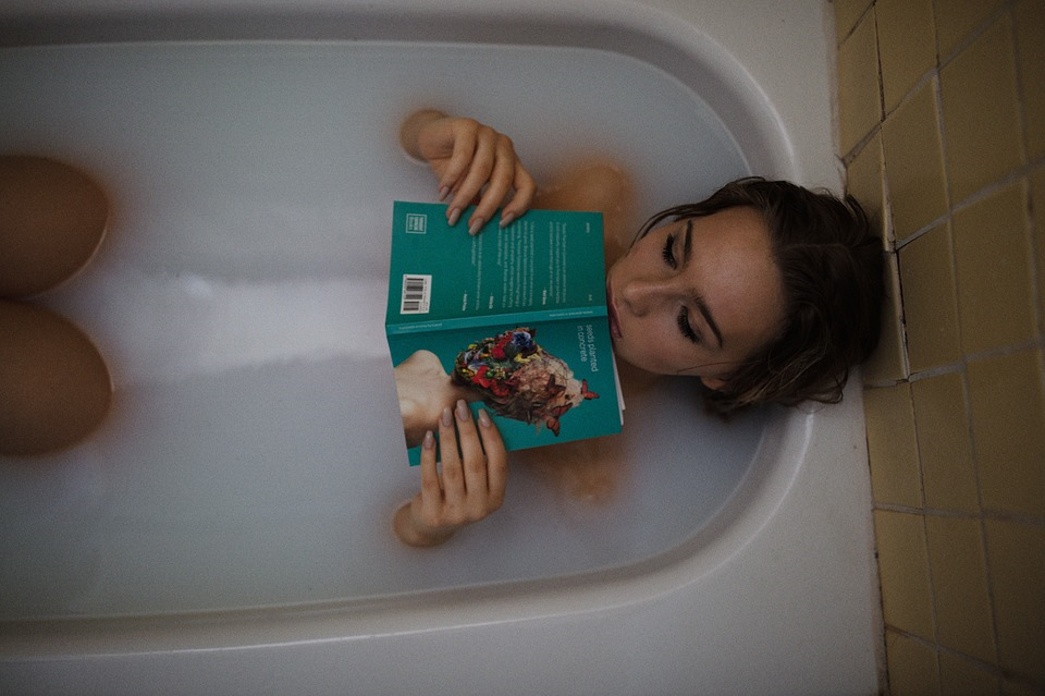 Woman Relaxing By Reading A Book In The Bath