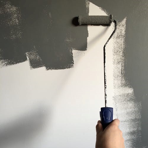 Using a roller to paint a wall