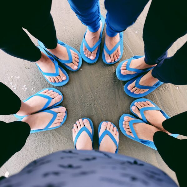 The feet of six people wearing blue flip flops
