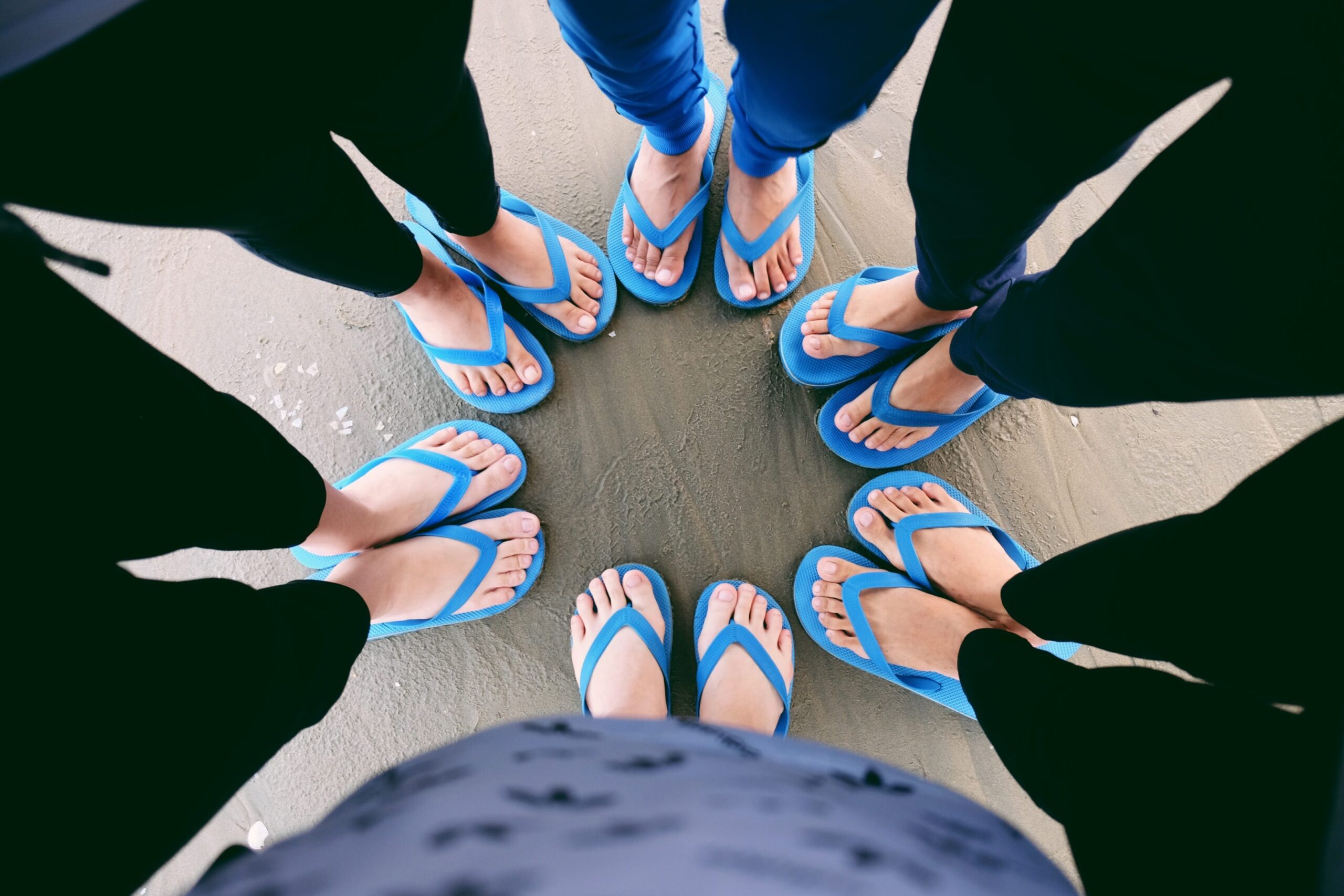 The feet of six people wearing blue flip flops