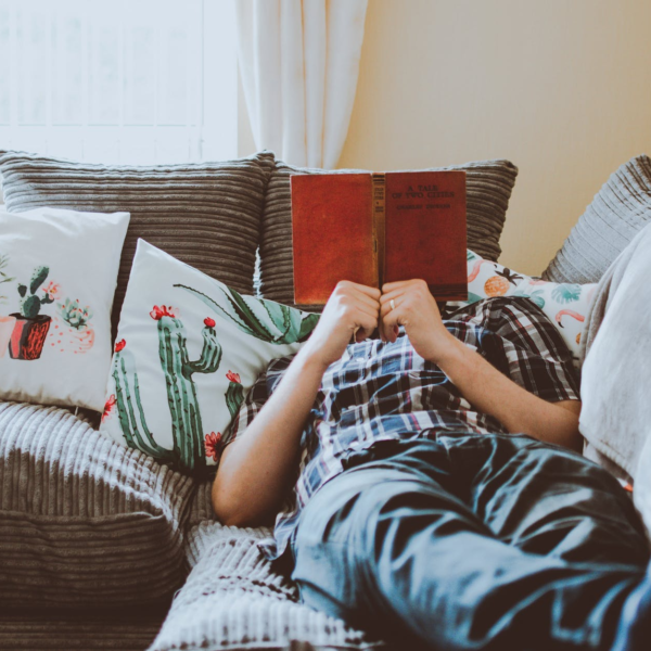 Person lying on couch whilst reading a book