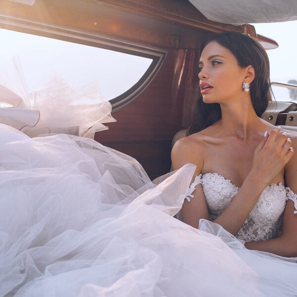 Bride wearing white sweetheart-neckline wedding dress inside vehicle