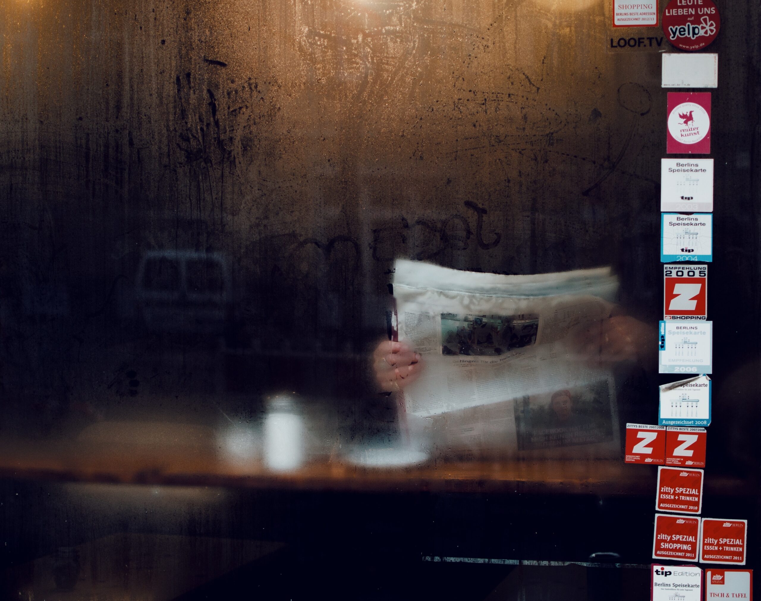 Person reading newspaper behind cafe window