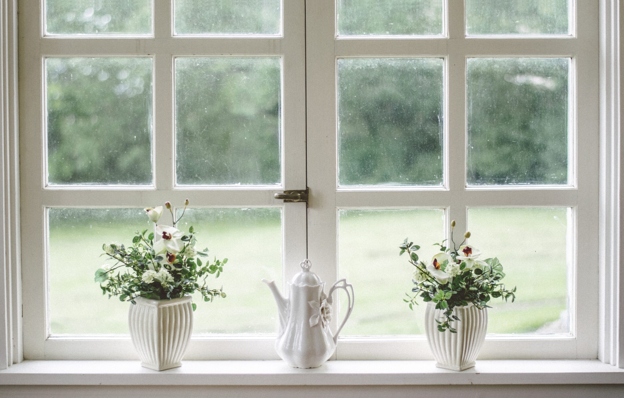 Flowerpots and porcelain teapot on windowsill