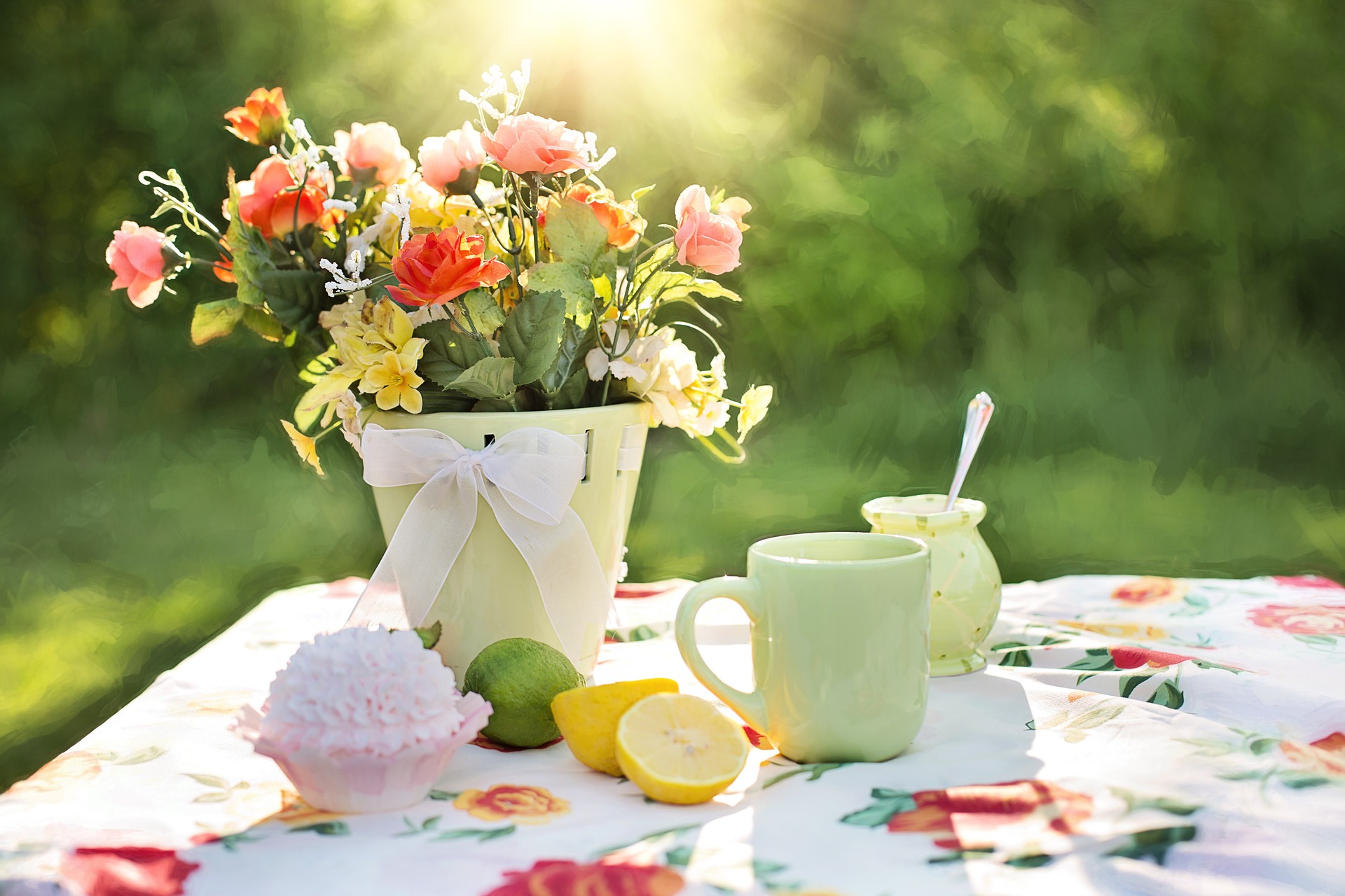Flowers, food and drink on a table in the sun