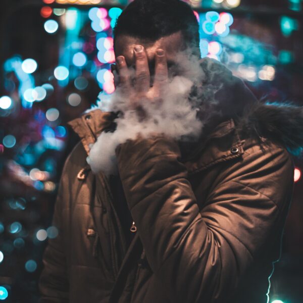 Man holding face whilst vaping
