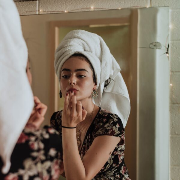 Woman putting on makeup in front of mirror