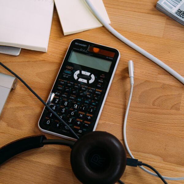 Black Sharp scientific calculator and headphones on a desk