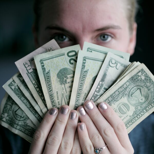 Young woman holding banknotes in front of face