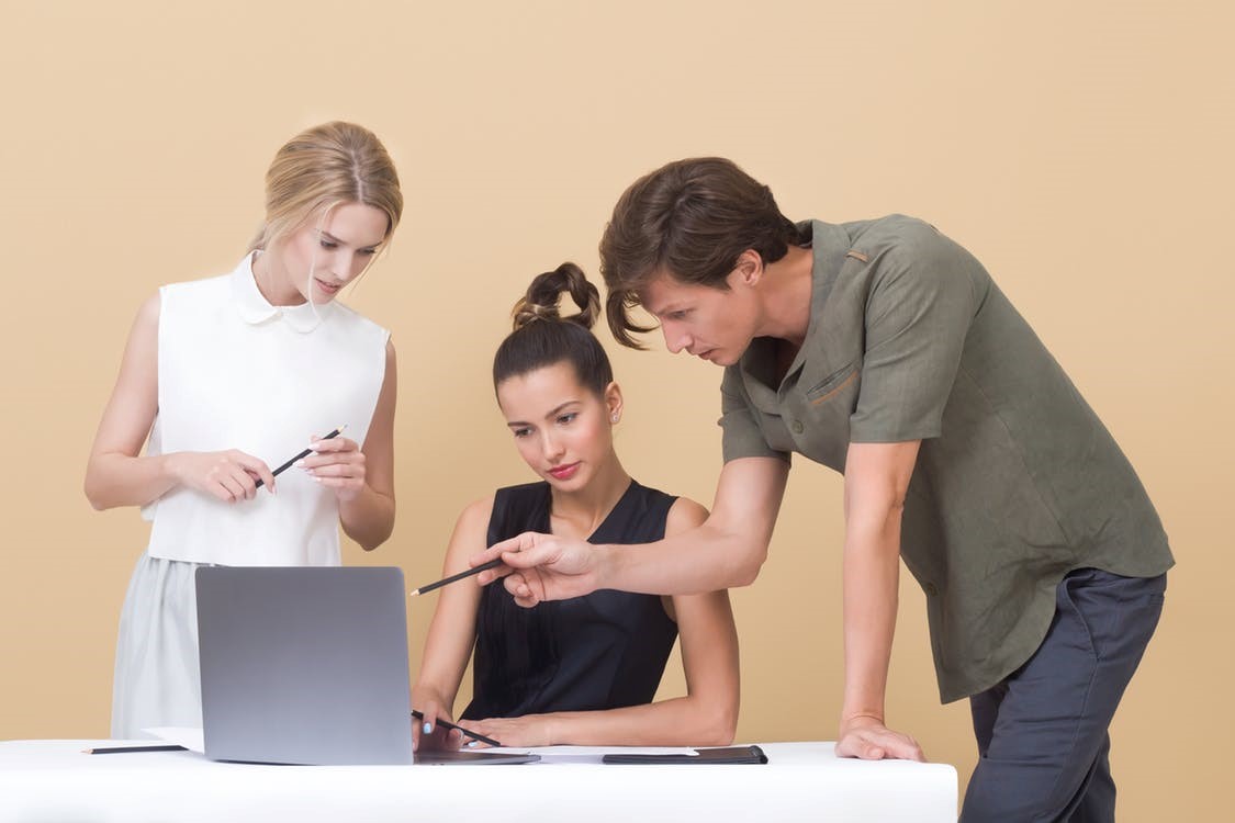 Two women and a man looking at a laptop