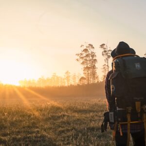 Person wearing a rucksack staring into the sunset