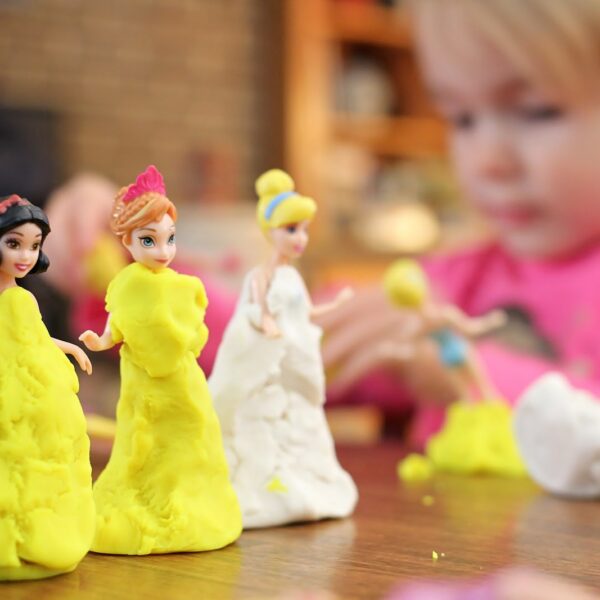 Girl making playdough dresses for her dolls