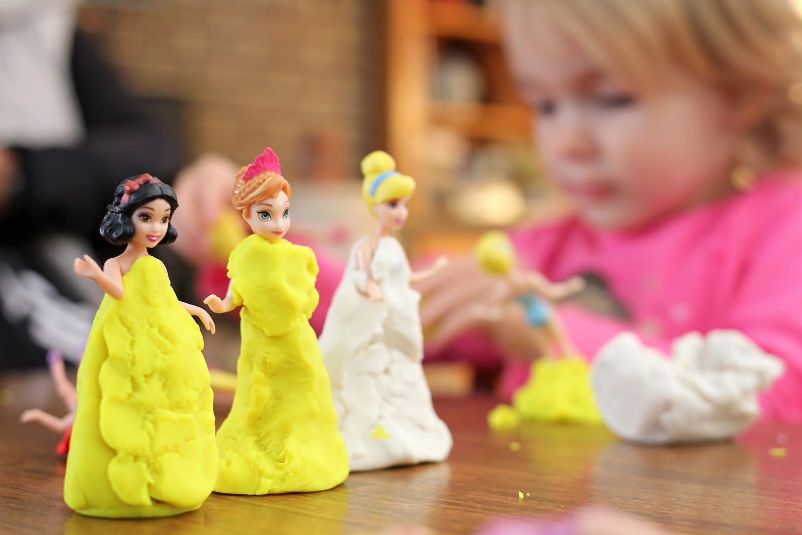 Girl making playdough dresses for her dolls