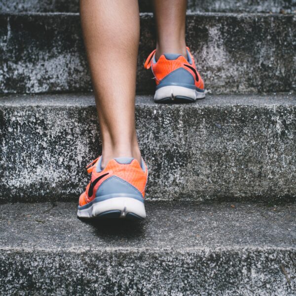 Person wearing orange and gray Nike shoes walking on gray concrete stairs