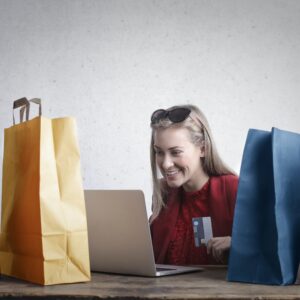 Woman surrounded by shopping bags buying something on laptop