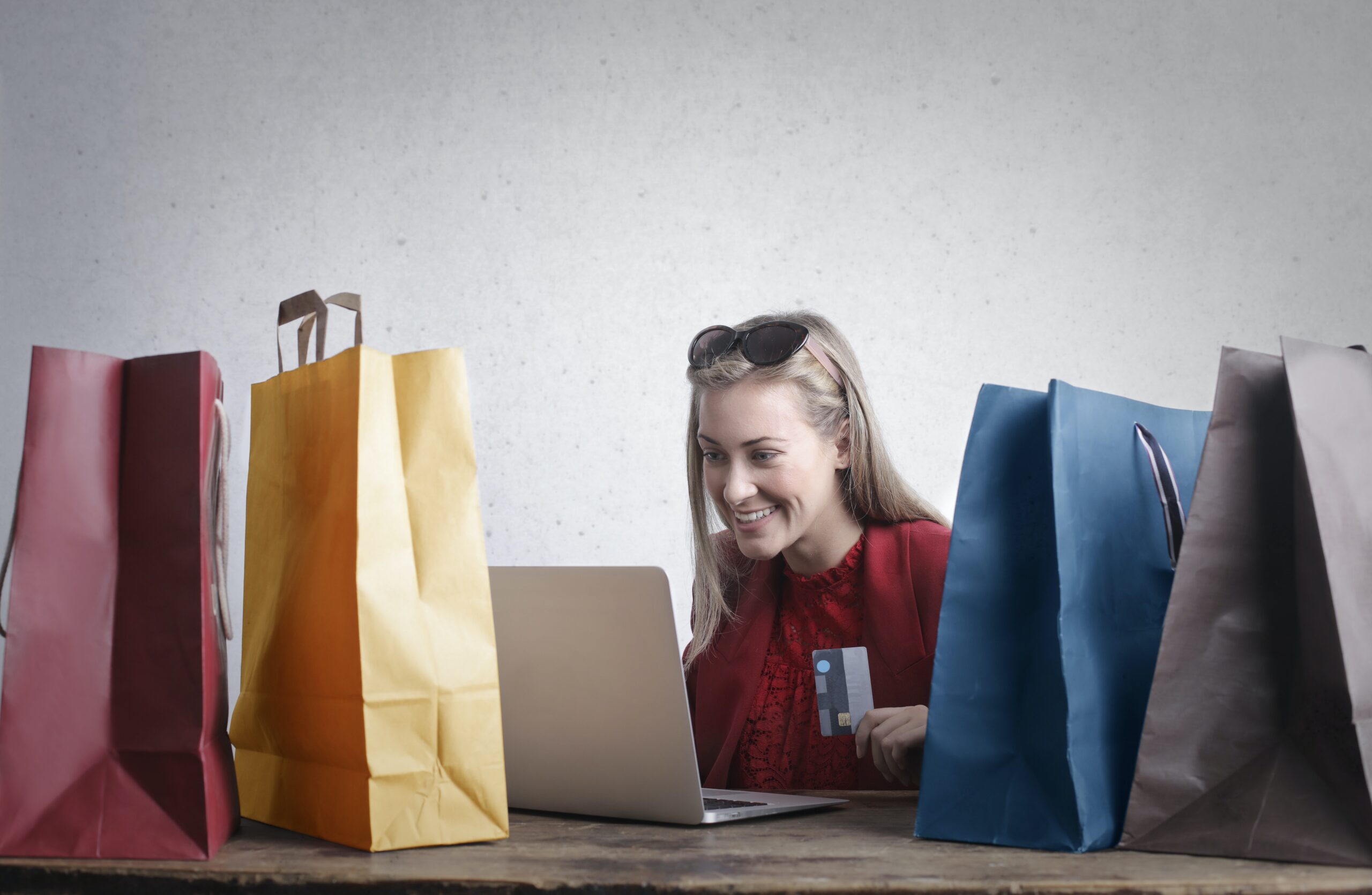 Woman surrounded by shopping bags buying something on laptop