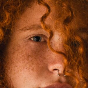 Woman with red curly hair and nose piercing