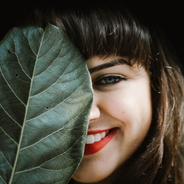 Woman smiling from behind a leaf