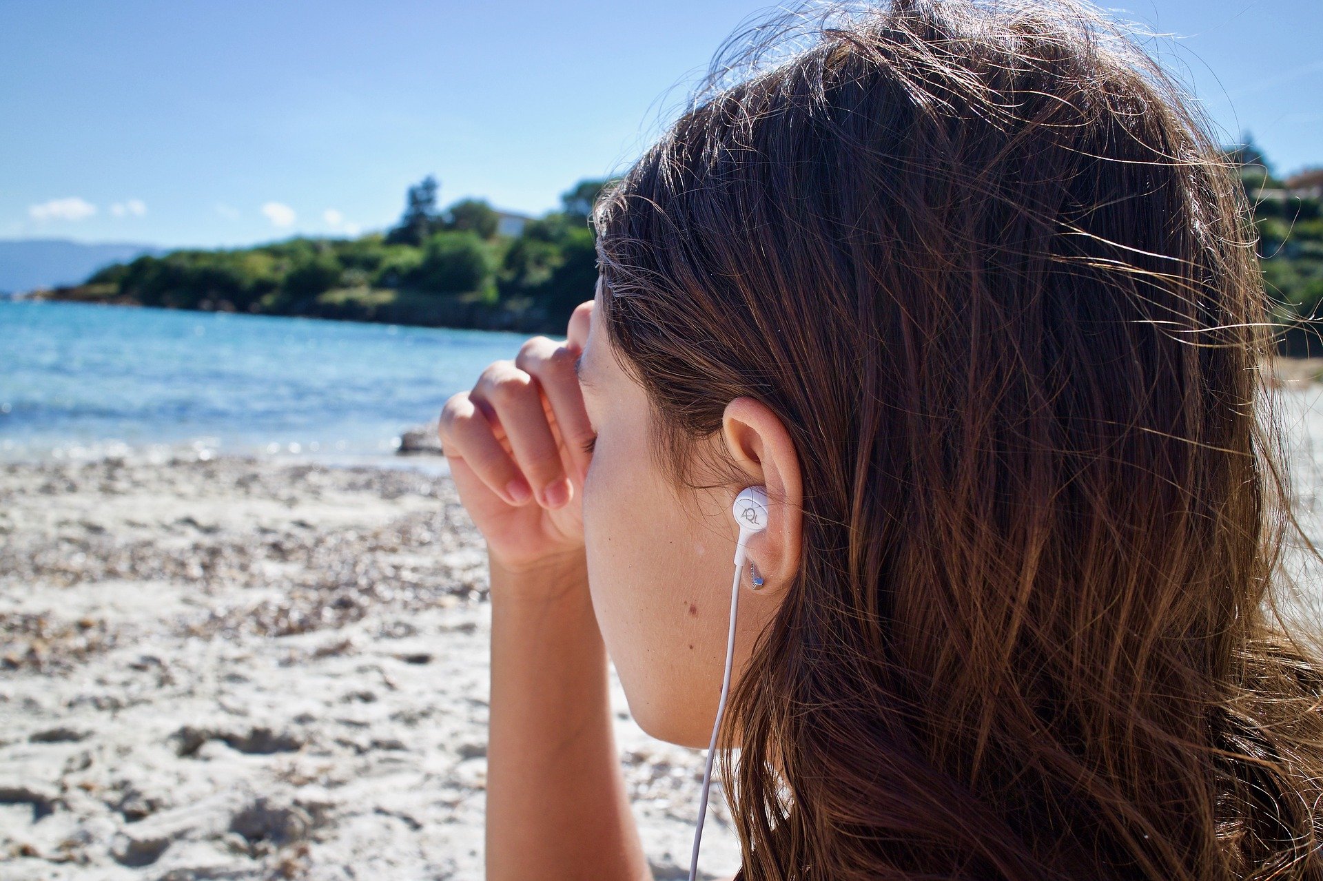 Woman meditating on beach whilst listening to music