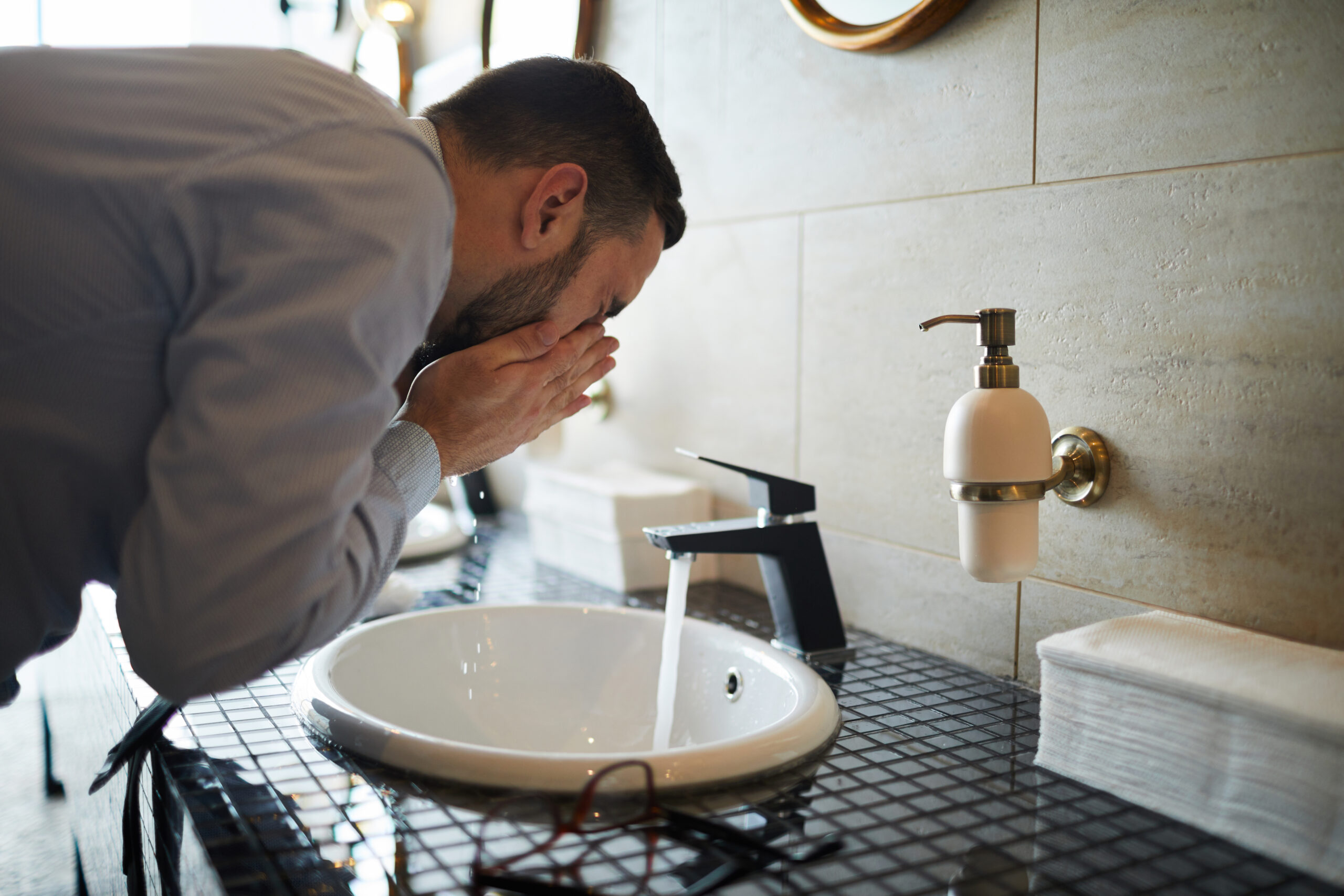 Man washing his face over sink