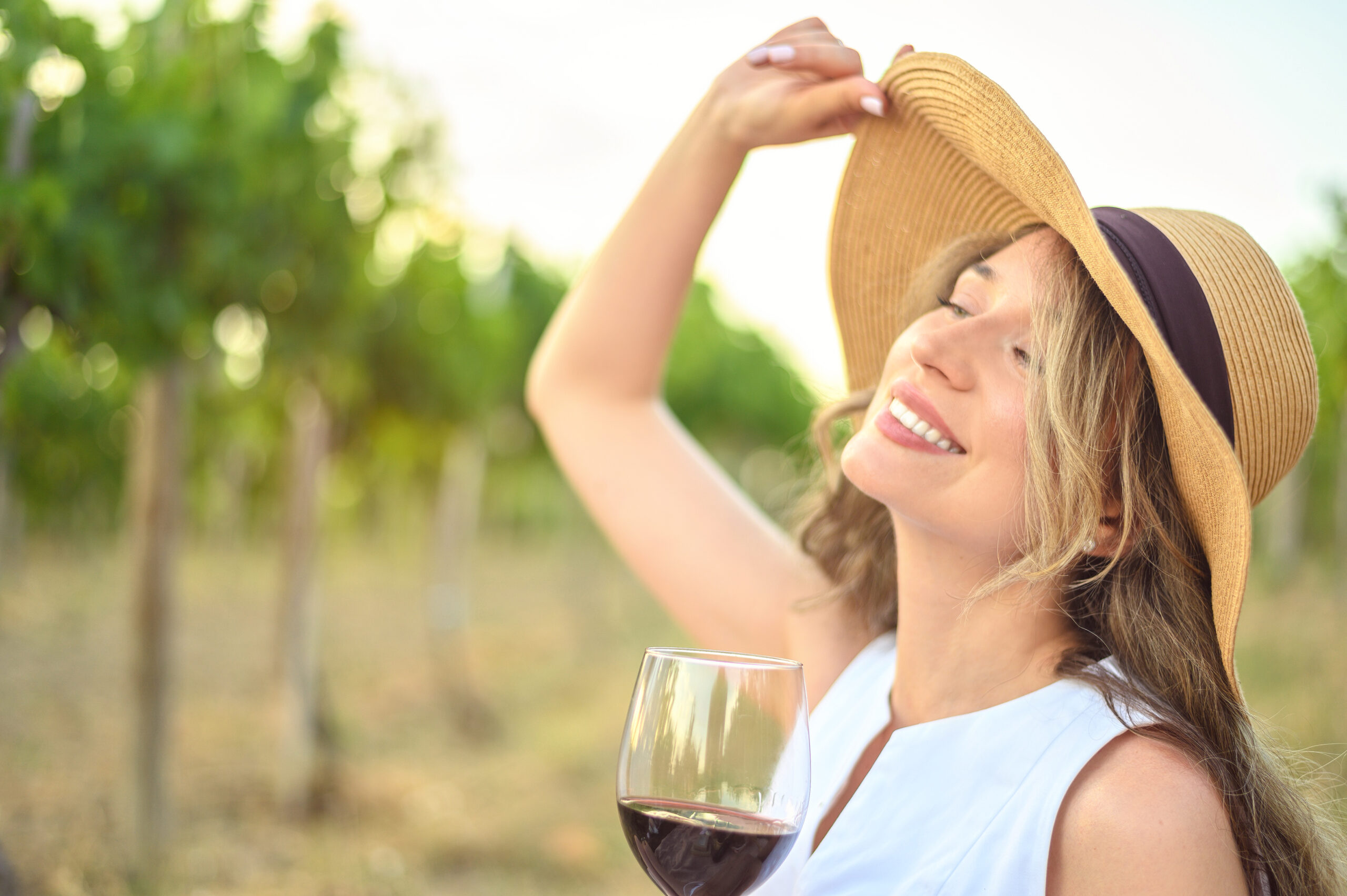 Woman wearing a sunhat whilst holding a glass of red wine