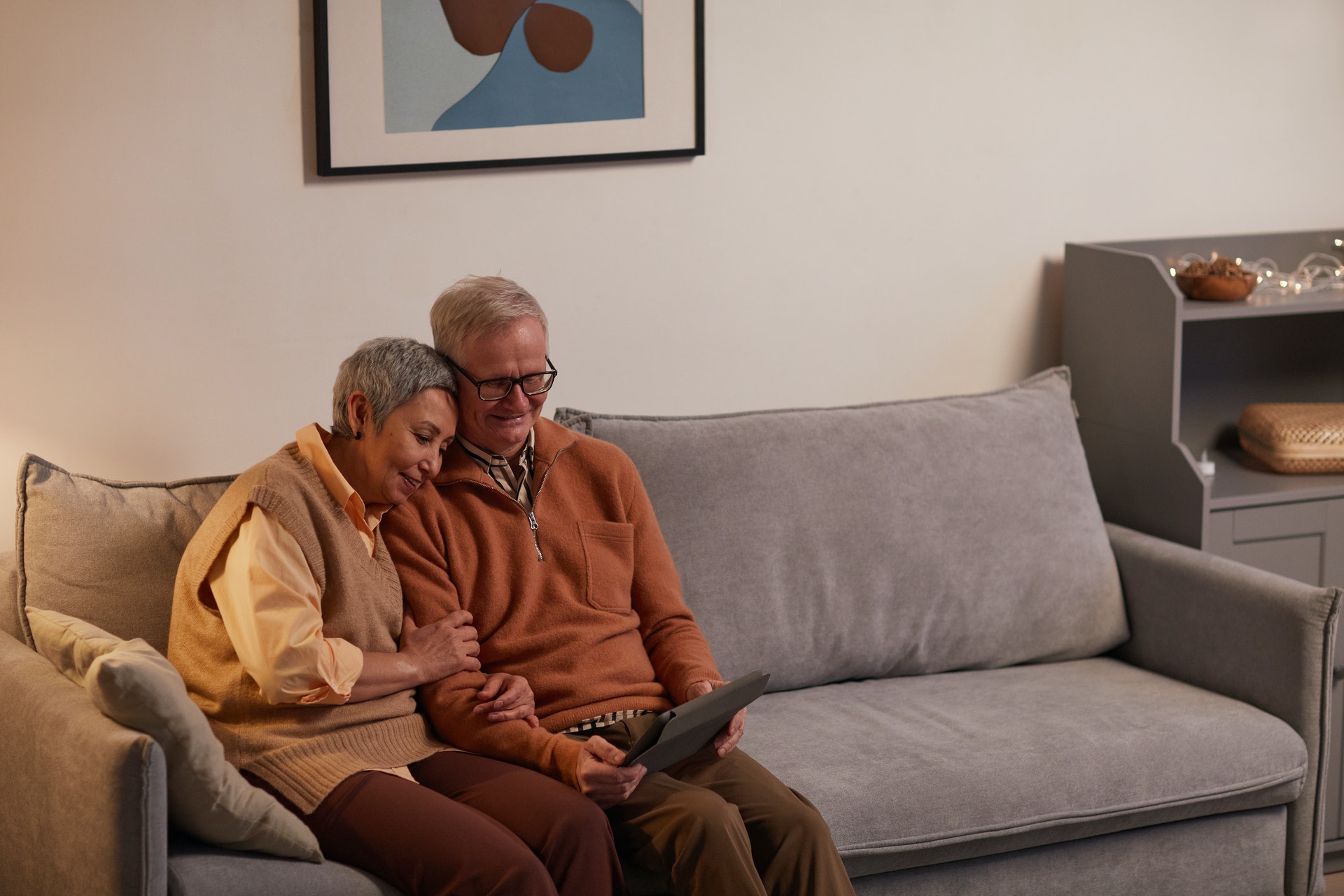 Elderly couple sitting on a couch looking at a tablet
