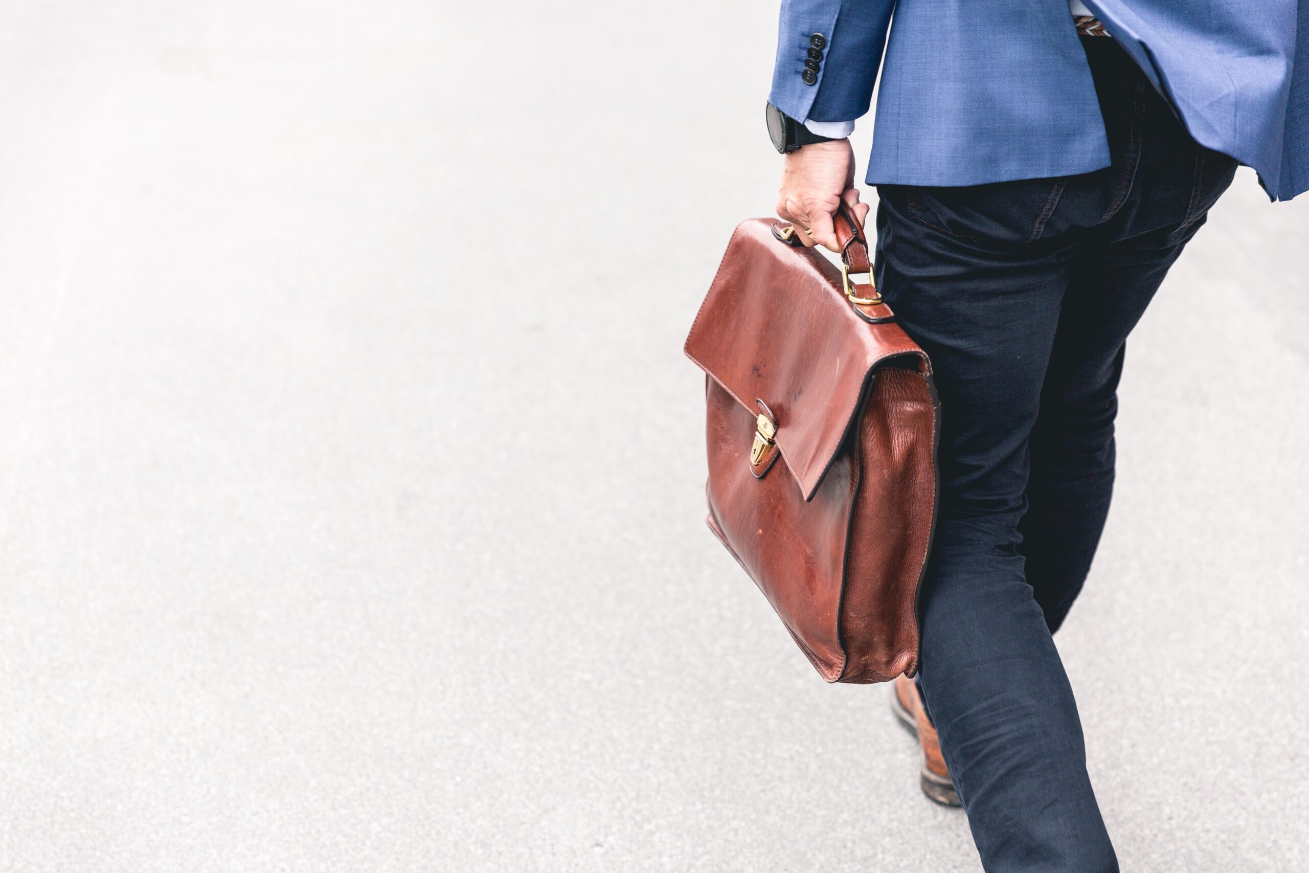 Person walking whilst holding a brown leather bag