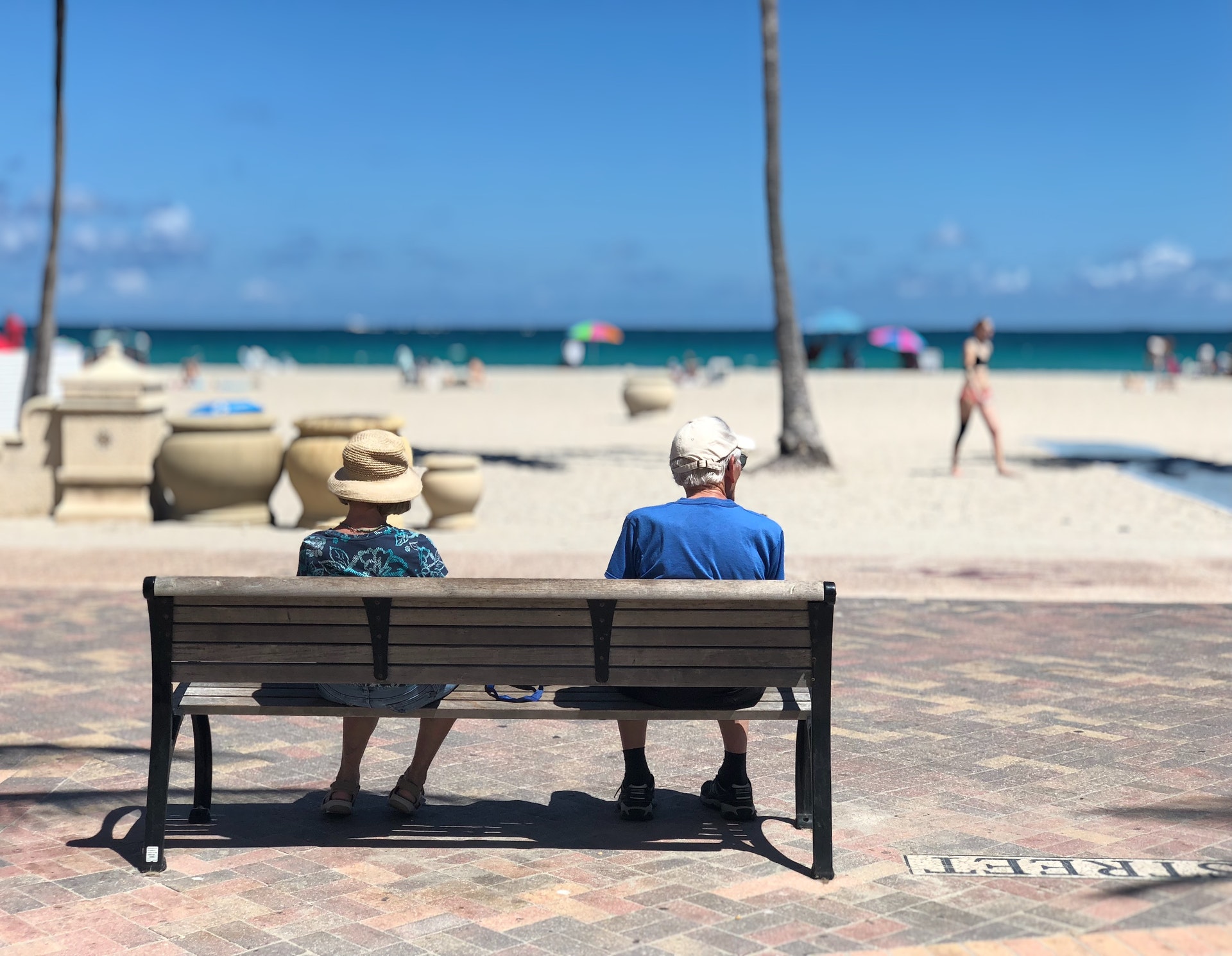 retired couple sitting on a bench looking at the beach