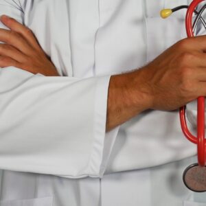 A doctor in a white coat holding a red stethoscope