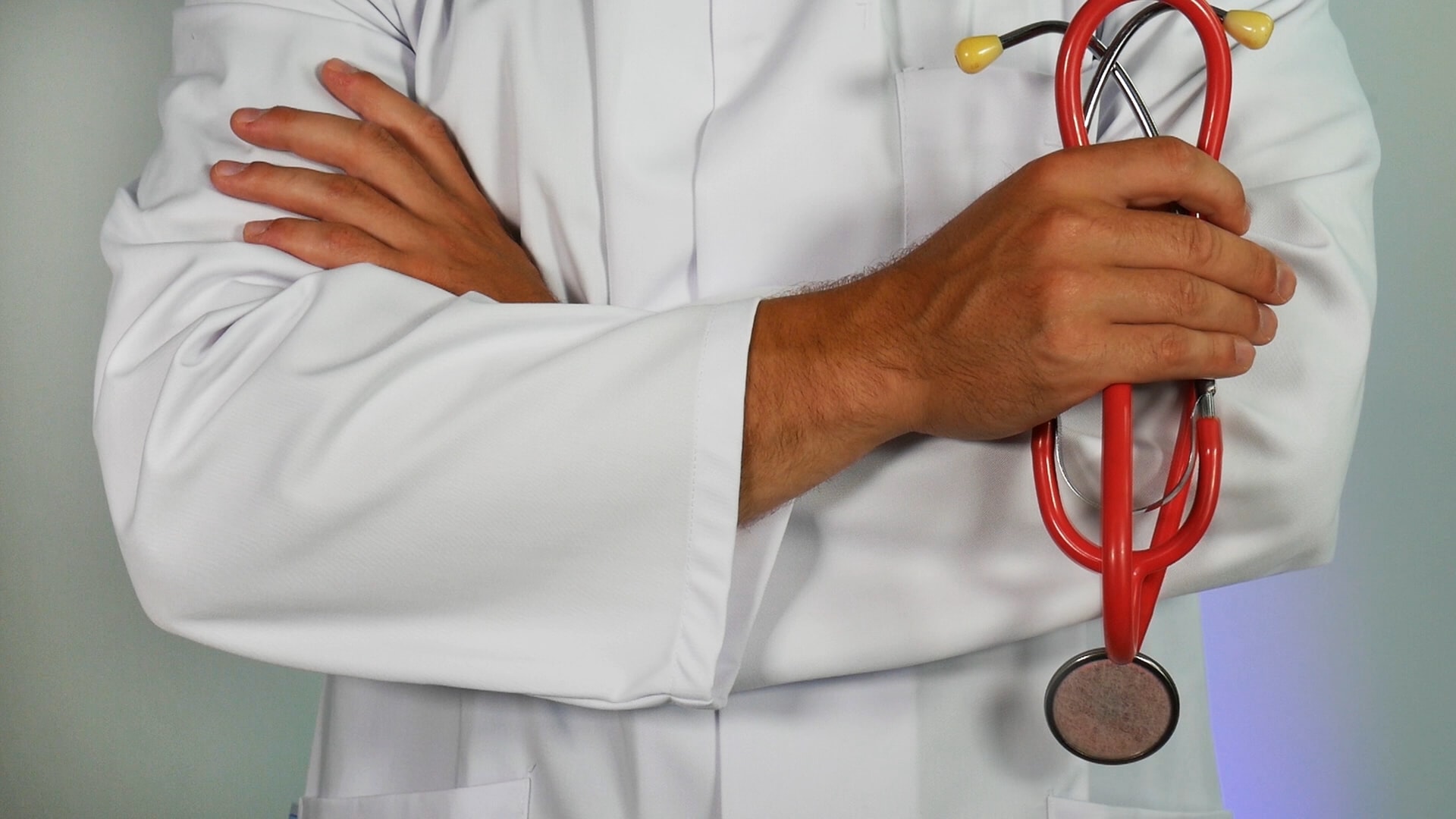 A doctor in a white coat holding a red stethoscope