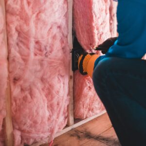 Man installing pink wall insulation