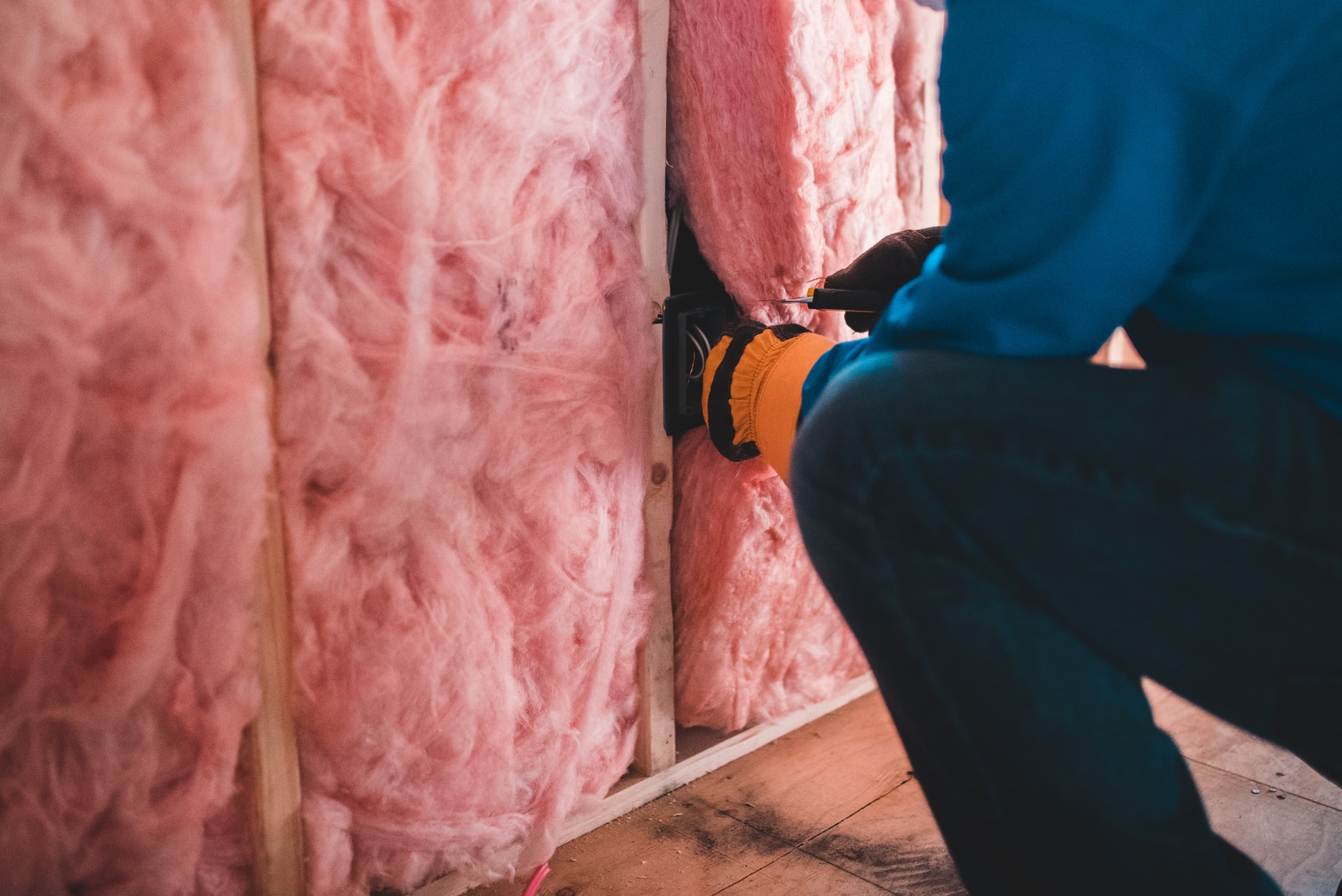 Man installing pink wall insulation