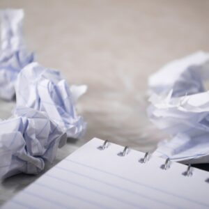 Crumped up balls of paper next to a notepad