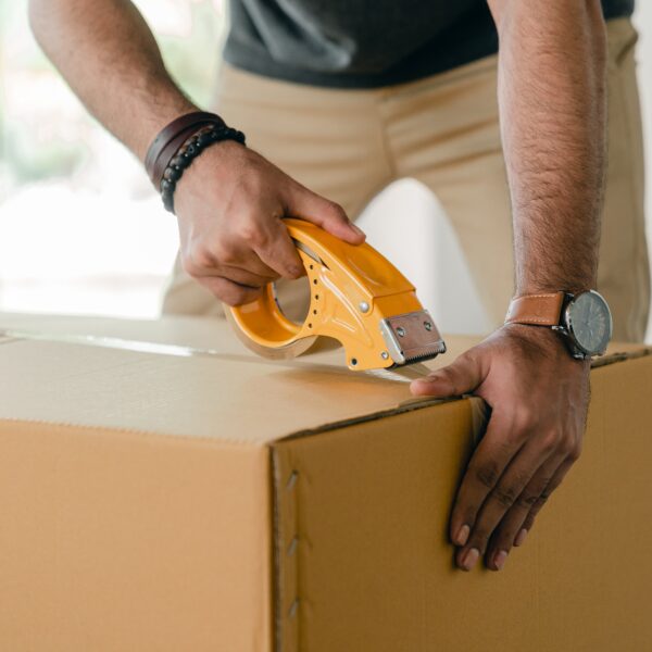 Man using a tape dispenser on a cardboard box