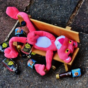 Pink Panther drunk on bench surrounded by bottles