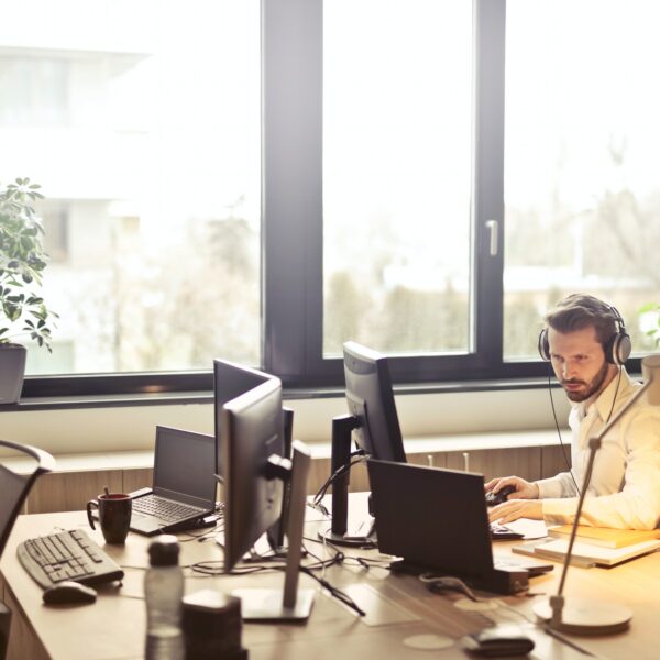 Man wearing headphones facing a computer monitor