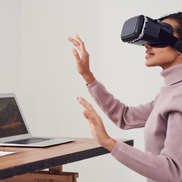 Woman sat in front of a laptop wearing a virtual reality headset