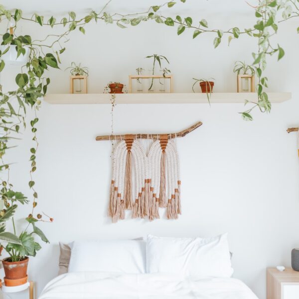 Bedroom with white walls, houseplants, fake vines, and macramé