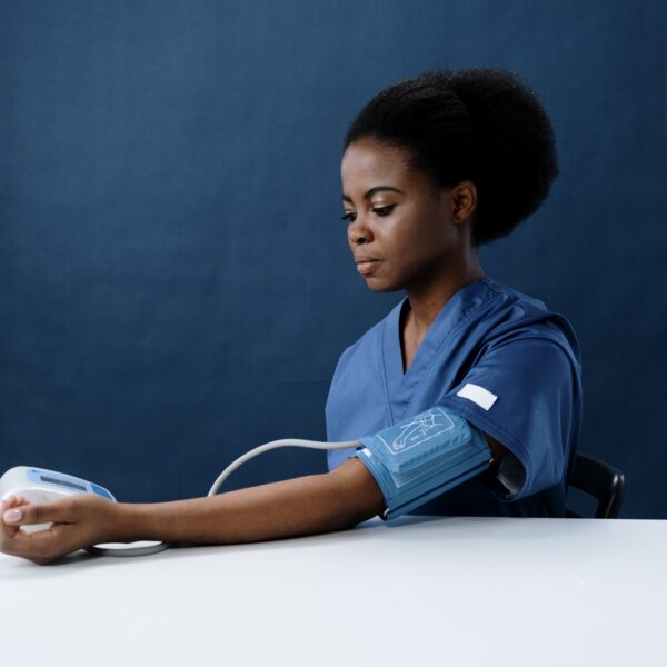 A healthcare worker measuring her own blood pressure using a sphygmomanometer