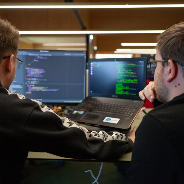 IT guys looking at a coding program on a laptop and monitor