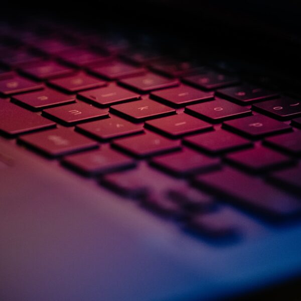 The keyboard of a laptop lit by the screen with shallow depth of field