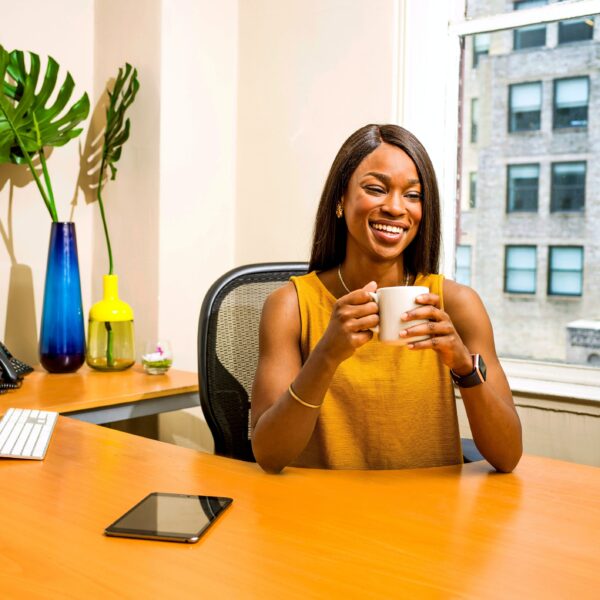 Woman holding a mug and smiling at her desk