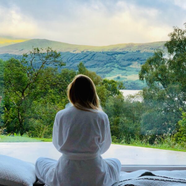 Woman in a robe looking at mountains through a window