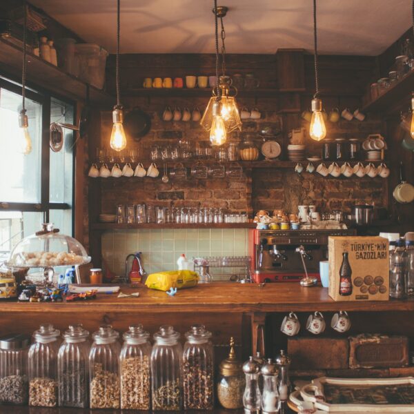 Photo of a counter at a cafe, with mugs, bottles, jars, and food