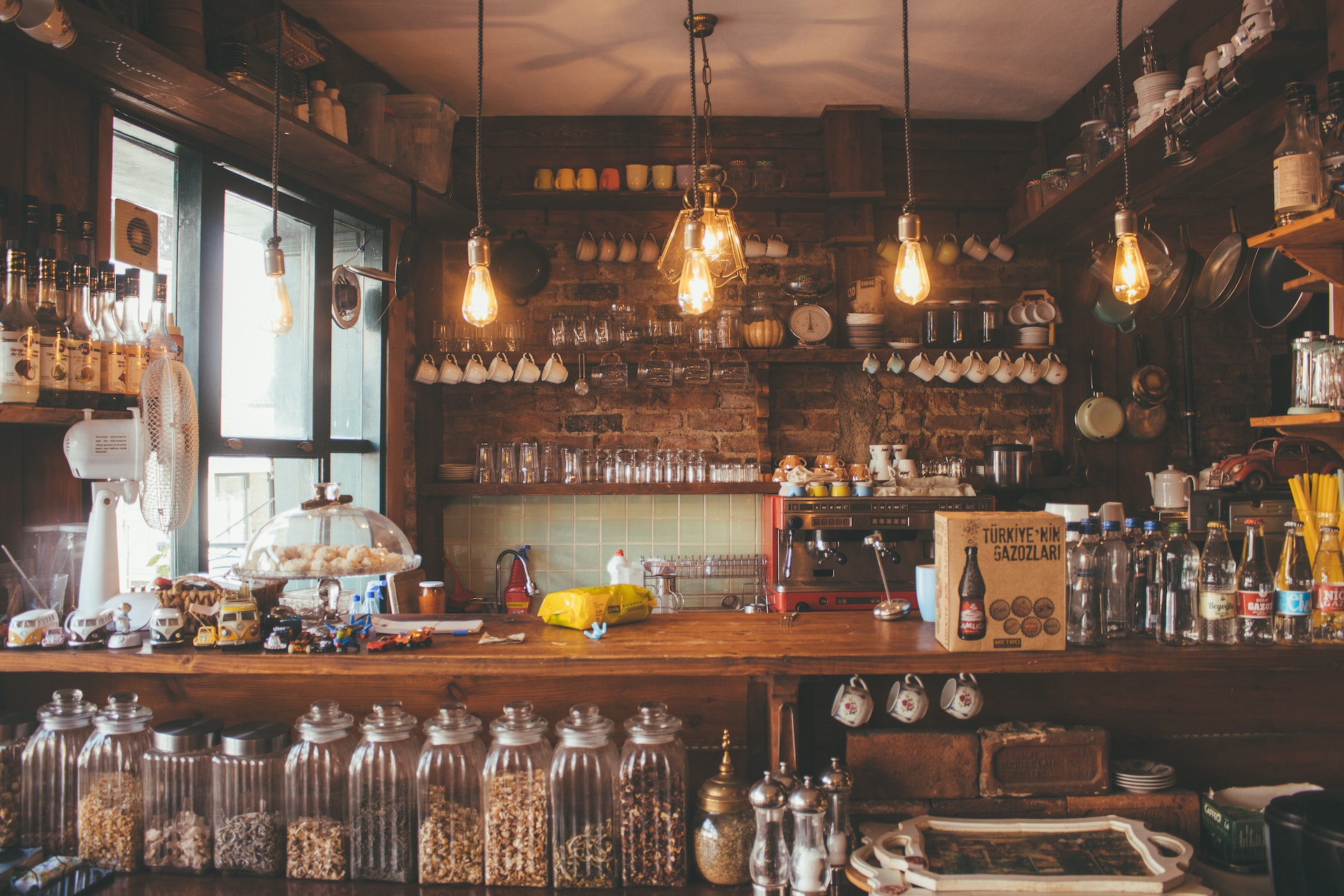 Photo of a counter at a cafe, with mugs, bottles, jars, and food